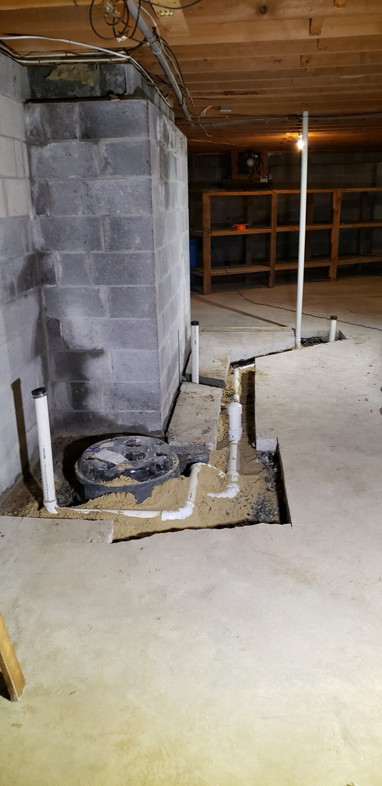 New sump pit and drain piping in a basement floor, installed by Tucker's Plumbing