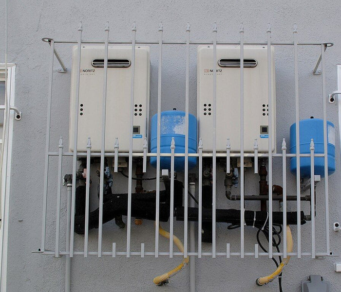 Two wall-mounted tankless water heaters with piping below