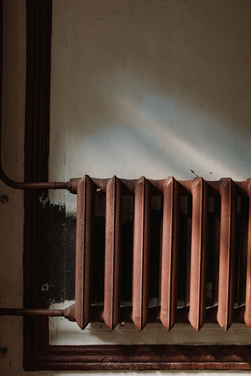Old rusty cast iron radiator on a wall