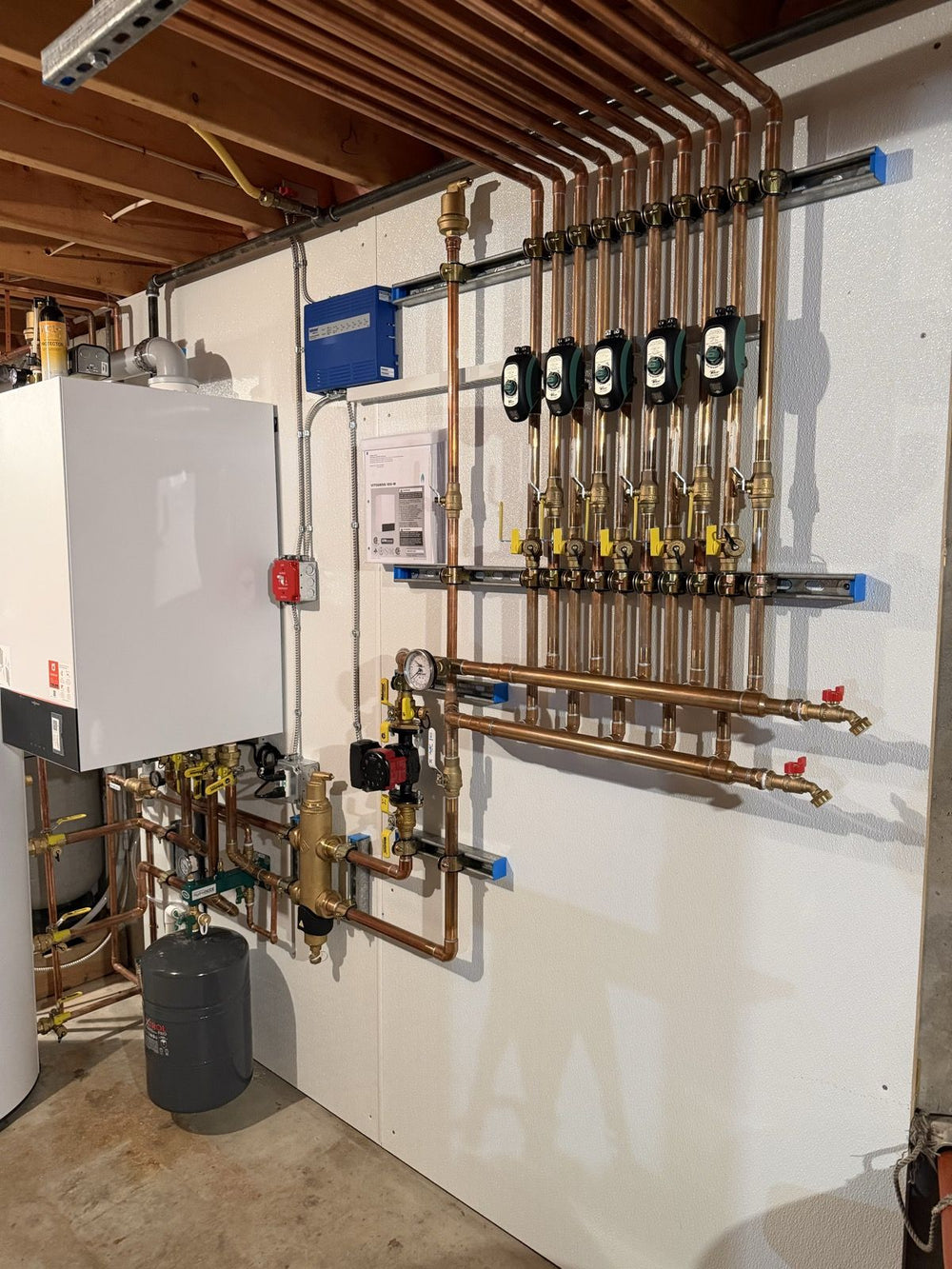 Hydronic zone manifold with circulator pumps and a wall-hung boiler, installed by Tucker's Plumbing