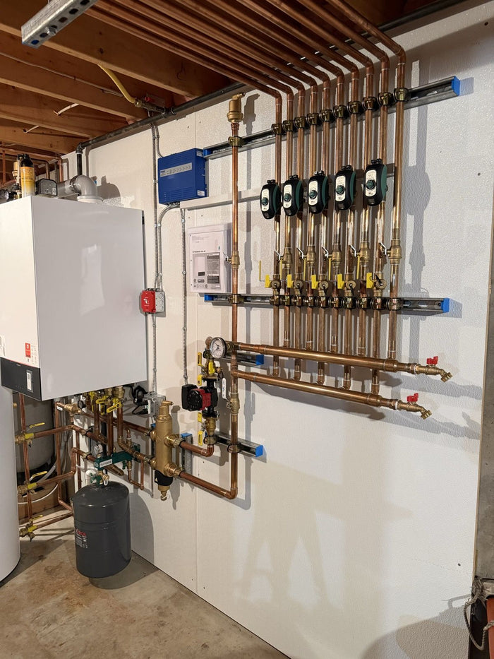 Hydronic zone manifold with circulator pumps and a wall-hung boiler, installed by Tucker's Plumbing