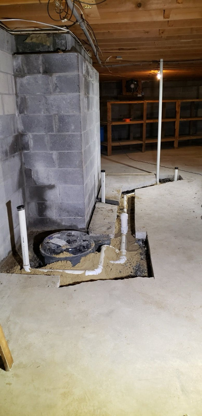 New sump pit and drain piping in a basement floor, installed by Tucker's Plumbing